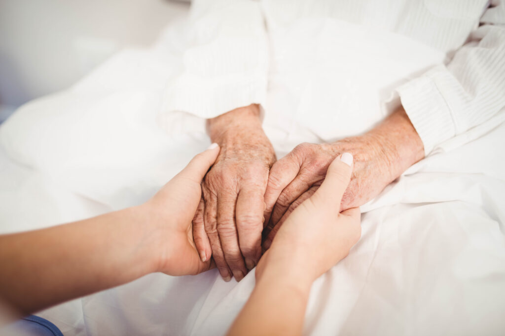 close up of senior woman and nurse holding hands